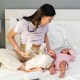 Mom sitting on bed next to baby and pumping breast milk. This article discusses sample breastfeeding and pumping schedules for newborns.